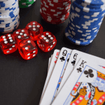 A deck of cards, stacks of poker chips and some dice on a table.