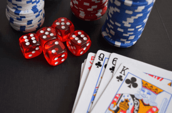 A deck of cards, stacks of poker chips and some dice on a table.