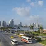 Alt Text: Panama City on a sunny day. You see a beach side street with tall skyscrapers in the background.