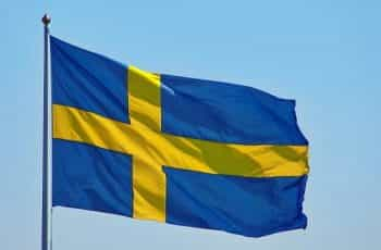 A flag of Sweden against a bright blue sky during the day.