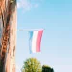 A red, white, and blue flag hoisted out of a window.