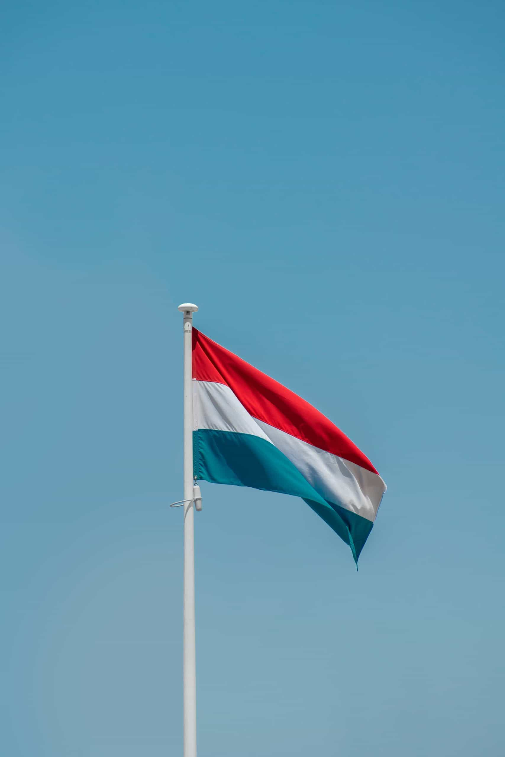 A red, white, and blue flag on a flagpole against a blue sky.