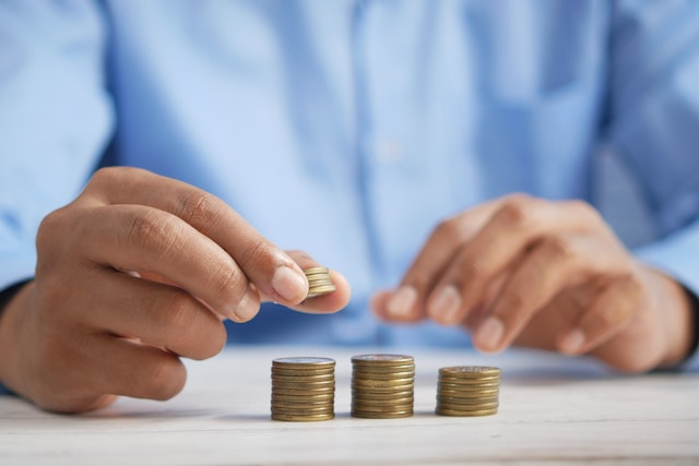 A person stacking coins in tiny piles on a table.