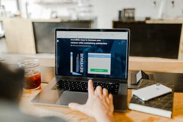 A person sitting in front of a laptop which is displaying an article on how to increase one’s revenue while keeping satisfaction consistent.